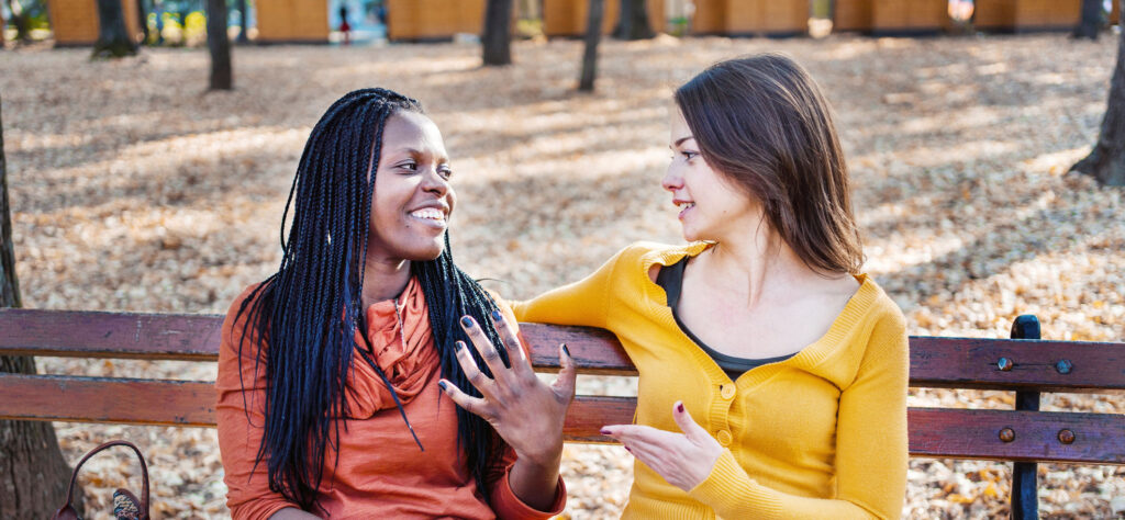 Friends talking on a bench, offering support during pregnancy.